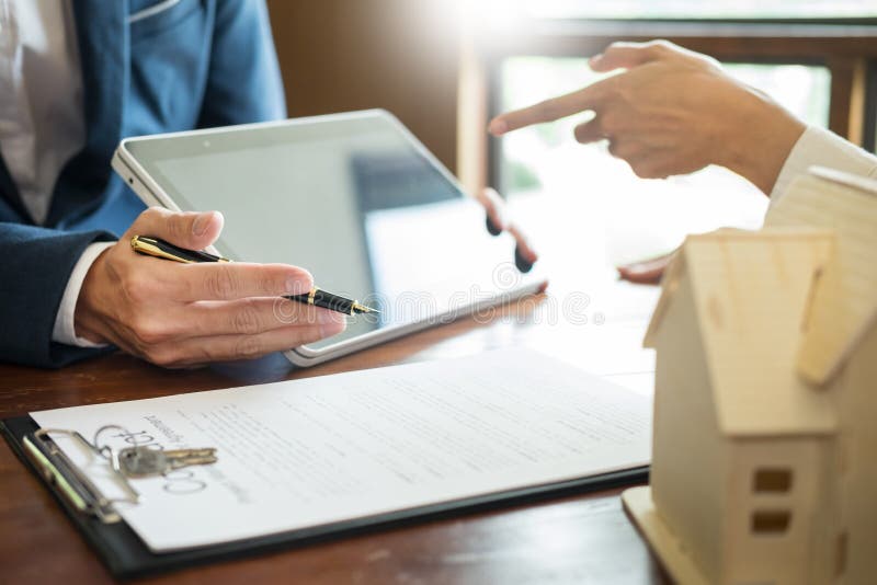 Businessman signs contract behind home architectural model.Discussion with a real estate agent rental company staff .at the stock image Businessman signs contract behind home architectural model.Discussion with a real estate agent rental company staff .at the stock image